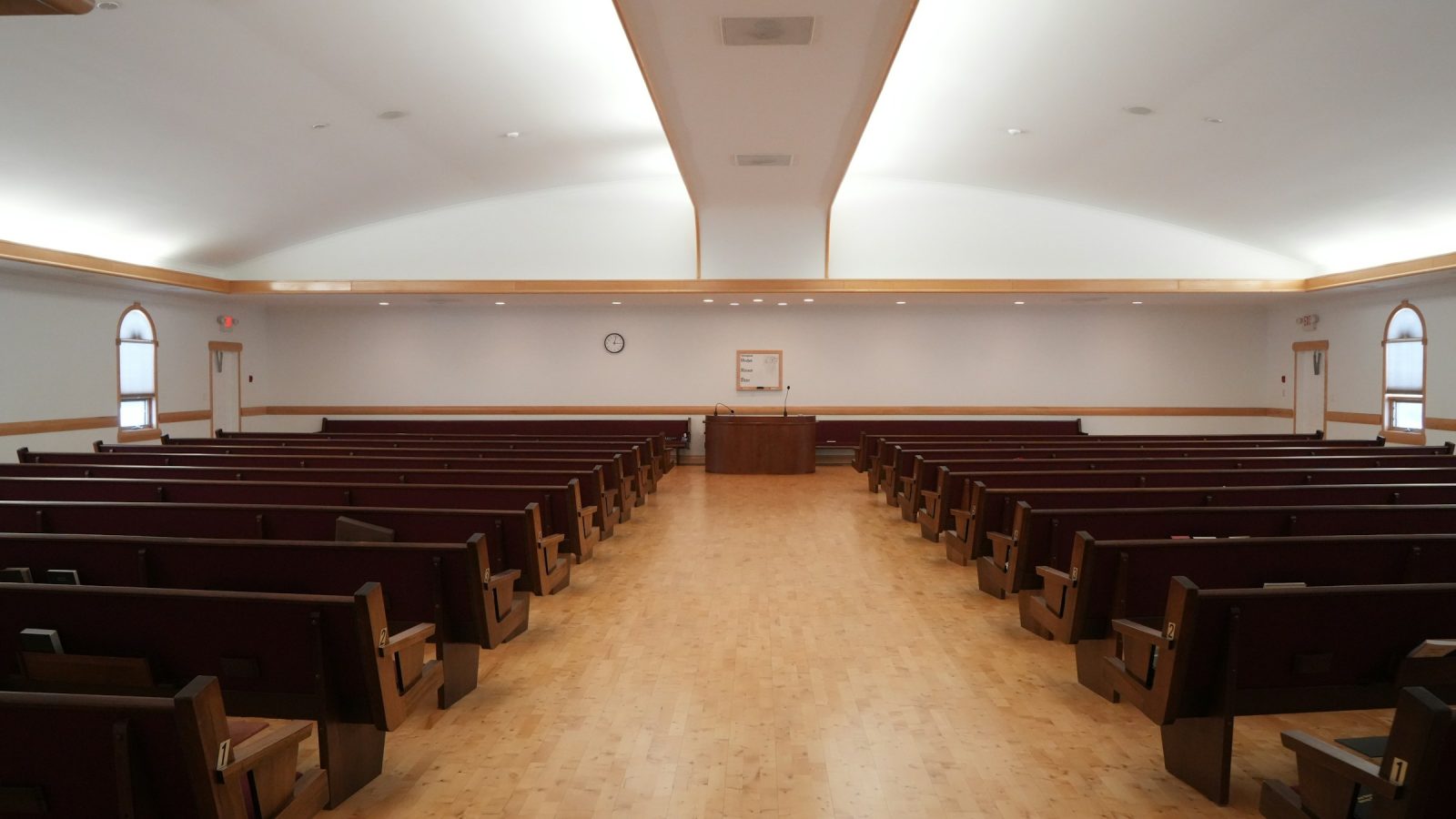 Rows of empty wooden pews in a bright church interior