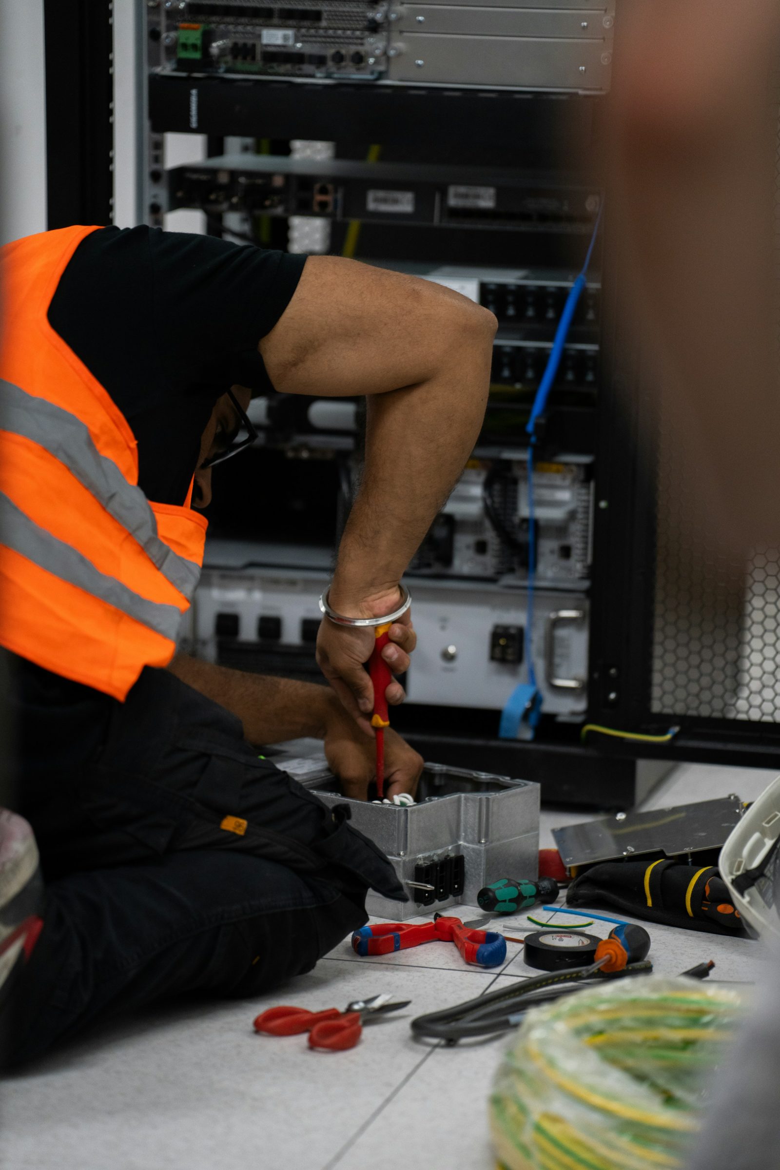 A technician servicing network equipment with hand tools